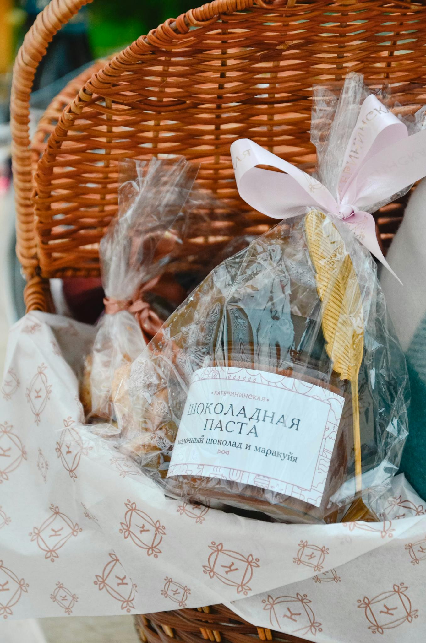 A wicker basket filled with assorted wrapped gifts and chocolate, perfect for festive occasions.