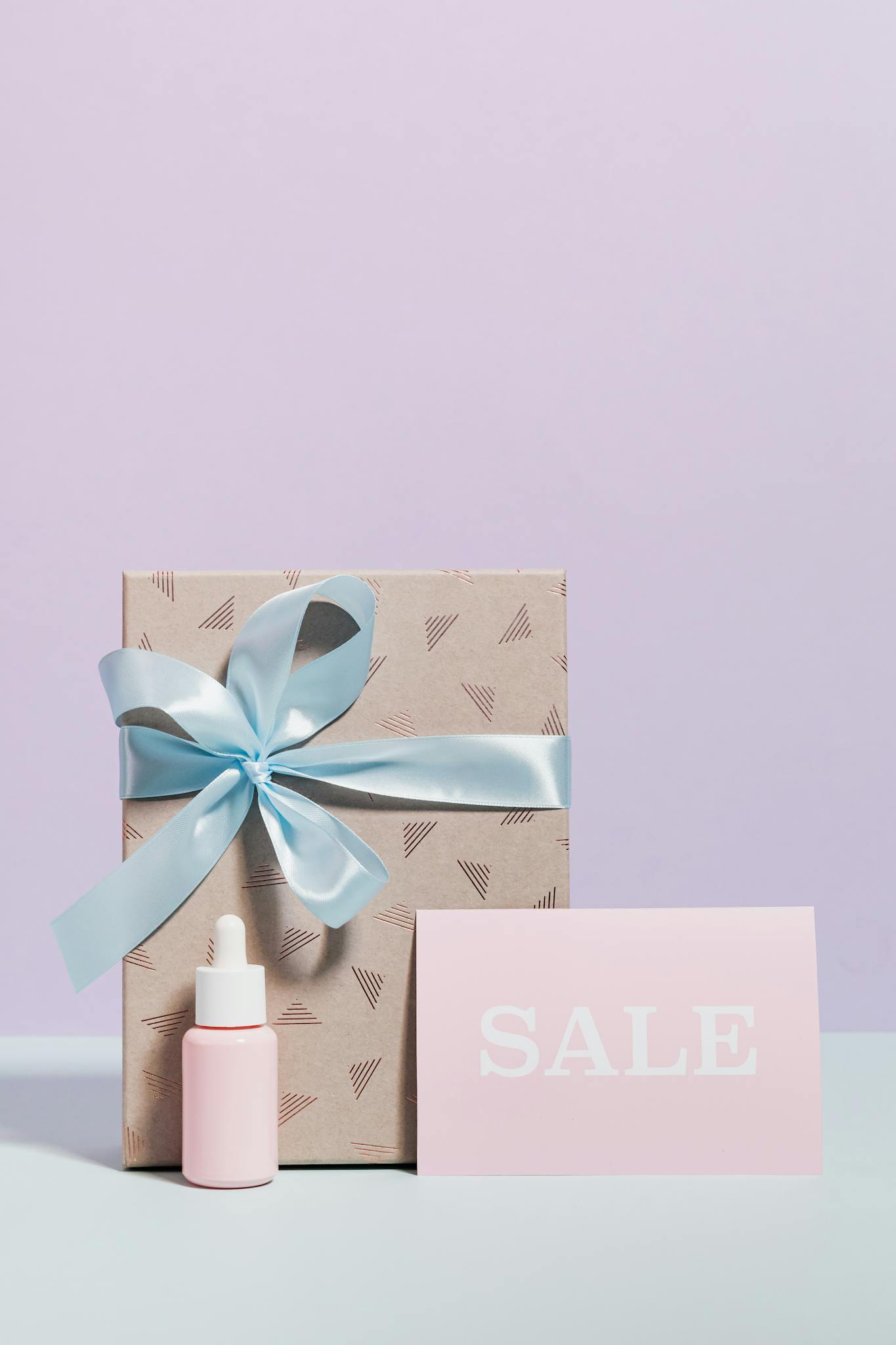 Chic gift box with blue ribbon and sale card against a minimalist backdrop.