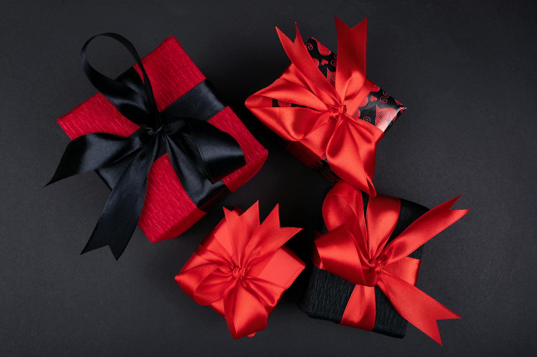 Stylish gift boxes wrapped in red and black with elegant ribbon bows, perfect for any celebration.